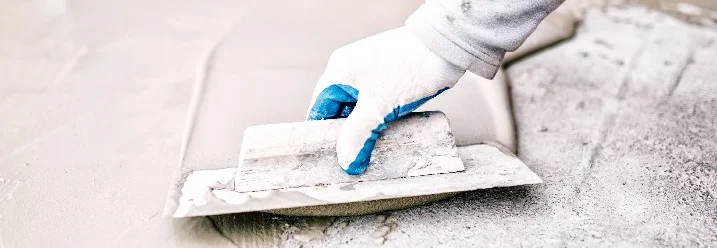 Hand mit Glättkelle glättet Betonboden